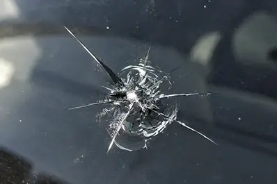 Kagylós és csillag alakú törés egy ponton az üvegen